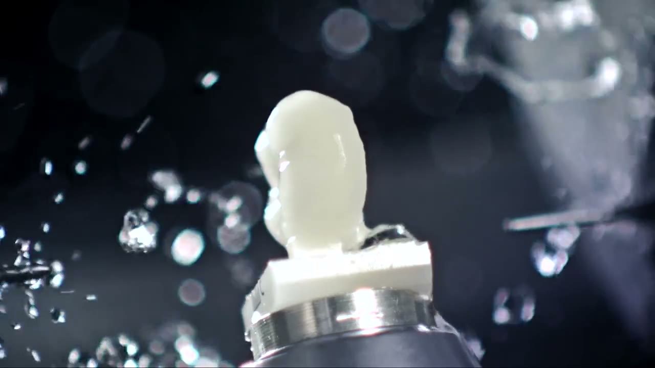 A ceramic block part-way through being milled into a crown, under water coolant